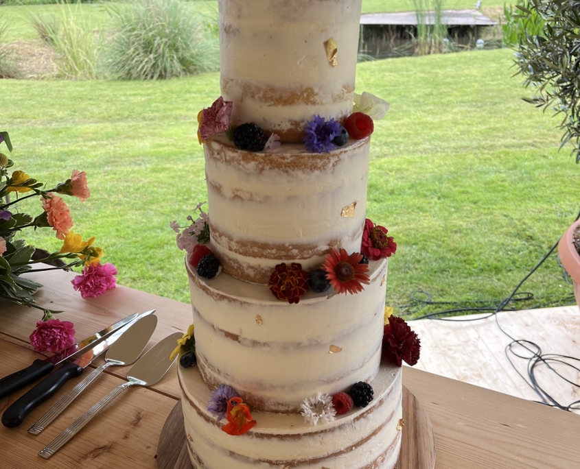 Naked cake bruidstaart met bloemen op een houten tafel buiten Naked cake bruidstaart met bloemen op een houten tafel buiten