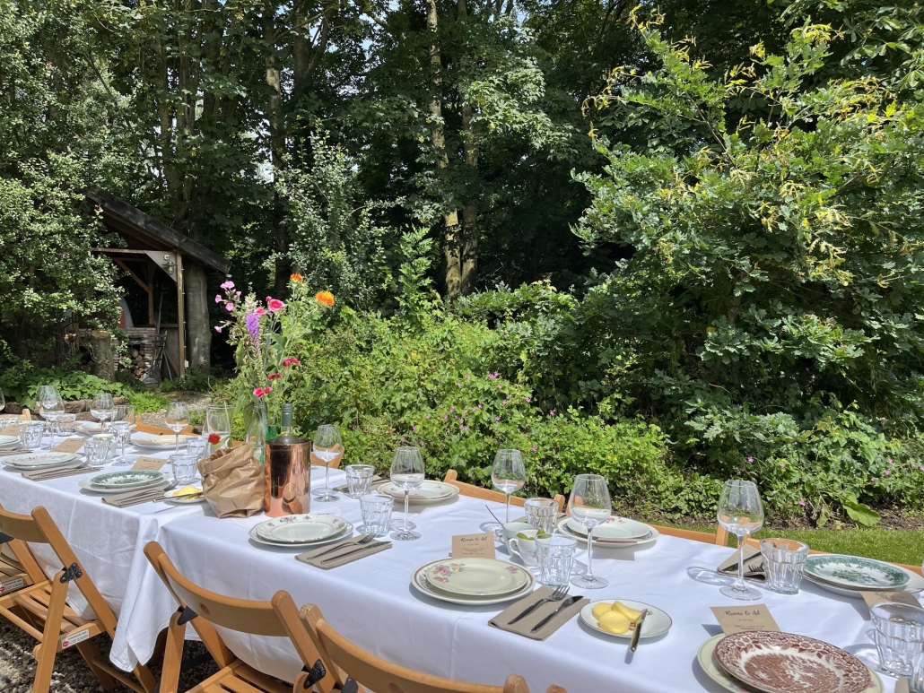Lange tafel met bloemen in een tuin aan het water Lange tafel met bloemen in een tuin aan het water, shared dining op locatie