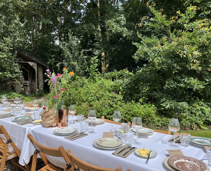 Lange tafel met bloemen in een tuin aan het water Lange tafel met bloemen in een tuin aan het water, shared dining op locatie